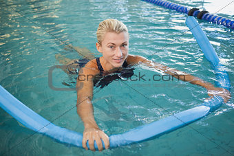 Fit female swimming with foam roller in pool
