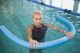 Fit female swimming with foam roller in pool
