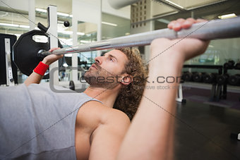 Young muscular man lifting barbell in gym