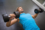 Young man exercising with dumbbells in gym