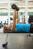 Side view of man exercising with dumbbells in gym