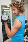 Handsome man exercising with dumbbell in gym