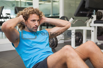 Handsome man doing abdominal crunches in gym