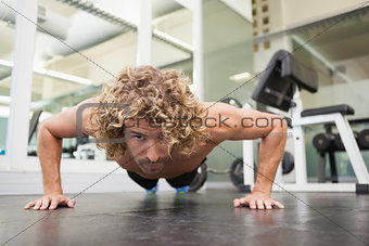 Handsome young an doing push ups in gym