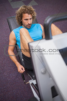 Young handsome man doing leg presses in gym