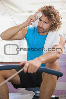 Tired man using resistance band in gym