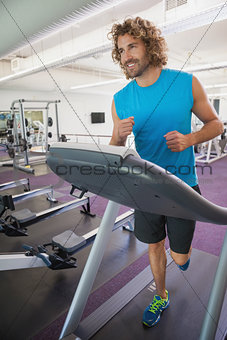 Smiling man running on treadmill in gym
