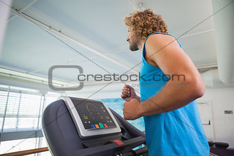 Side view of man running on treadmill in gym
