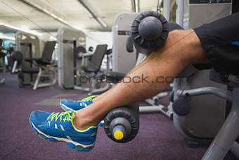 Low section of man doing leg workout at gym