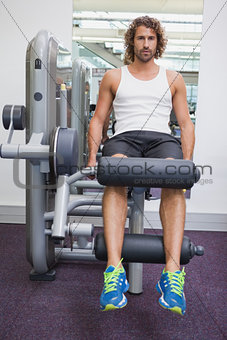 Portrait of handsome man doing leg workout at gym