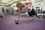 Side view of man exercising with kettle bells in gym