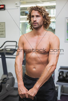 Shirtless man exercising with kettle bell