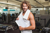 Smiling handsome trainer with clipboard in gym