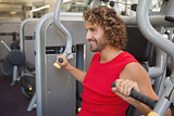Handsome smiling man working on fitness machine at gym