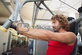 Side view of man working on fitness machine at gym
