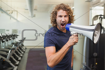 Portrait of trainer shouting into bullhorn in gym