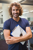 Smiling handsome trainer with clipboard in gym