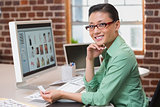 Smiling female photo editor using computer in office