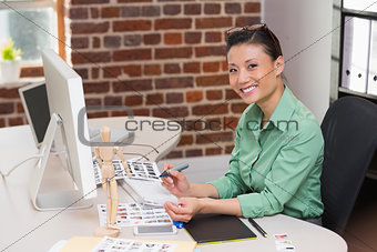Smiling female photo editor using computer in office