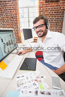 Smiling photo editor using computer in office