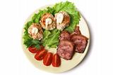Pork, stuffed eggs, tomatoes and lettuce on a plate.