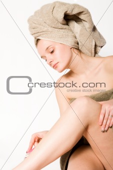 Young woman is shaving her leg