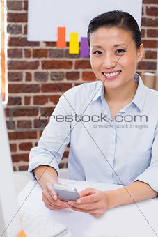 Smiling female executive text messaging in office