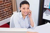 Smiling executive using mobile phone at desk