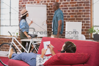 Relaxed casual man lying and writing note on couch