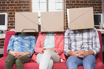 Team sitting on couch with boxes over heads