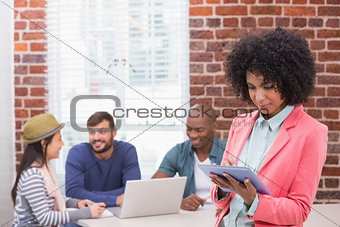 Woman using digital tablet with colleagues behind in office