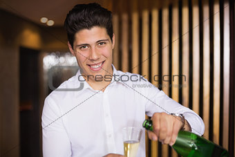 Handsome man smiling at camera pouring champagne