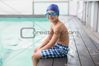 Cute little boy sitting poolside