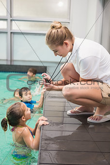 Pretty swimming coach showing boy his time