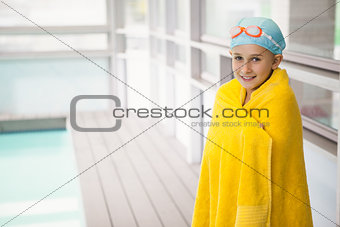 Cute little girl standing poolside wrapped in towel
