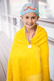 Cute little girl standing poolside wrapped in towel