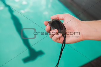 Swimming coach holding stopwatch poolside