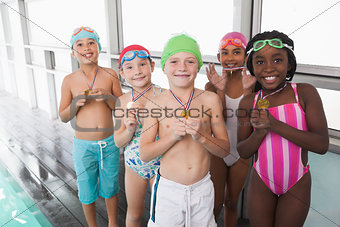 Cute little kids standing poolside with medals