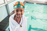 Cute little boy wrapped in towel with medal poolside