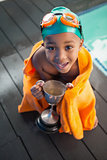 Cute little boy wrapped in towel with trophy poolside