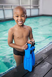 Little boy holding flippers by the pool