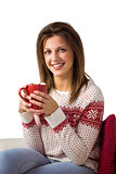 Happy young woman sitting on sofa holding mug