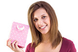 Young woman holding a pink gift bag smiling at camera