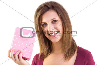 Young woman holding a pink gift bag smiling at camera