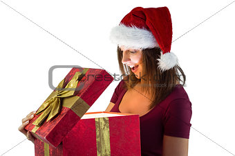 Pretty woman in santa hat opening a gift smiling at it