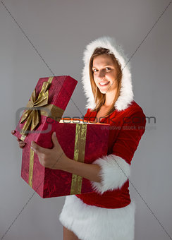 Smiling girl opening a gift and looking at the camera