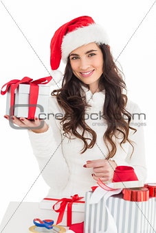 Cheerful brunette in santa hat holding gift