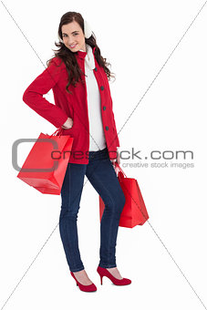 Cheerful brunette in winter clothes posing and holding shopping bags