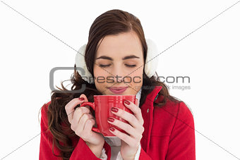 Woman in winter clothes enjoying a hot drink eyes closed