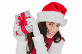 Happy brunette in santa hat holding gift